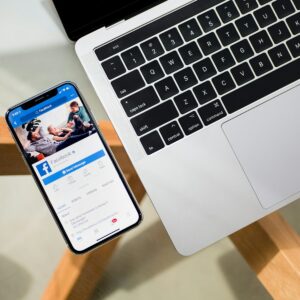 iPhone X beside MacBook, Facebook icon, what to do if Facebook account is hacked