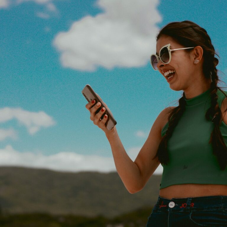 woman in green tank top holding smartphone during daytime, Best Practices for Traveling Overseas with a Mobile Device